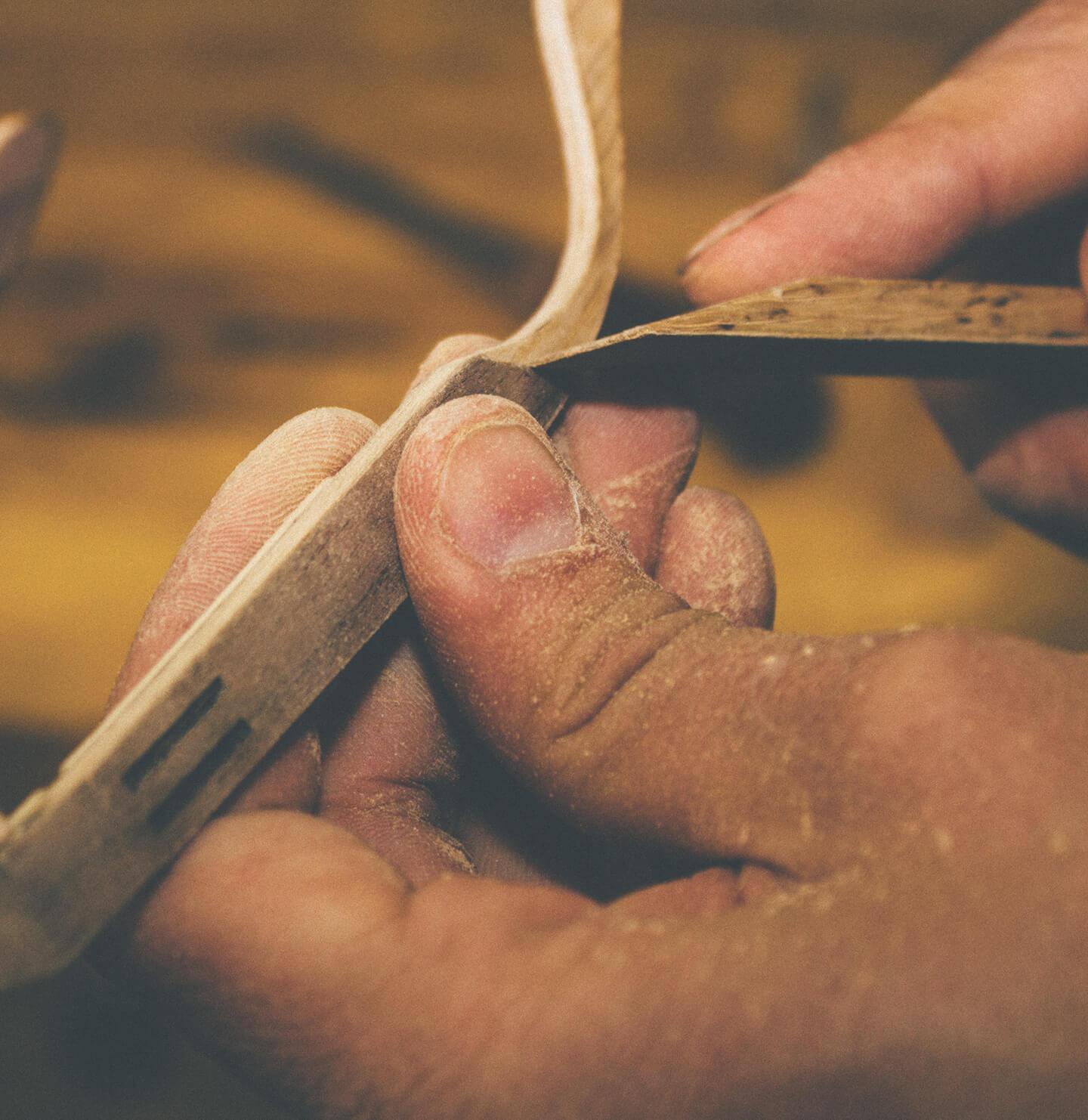 woodworker using a sanding block to smooth down the temples on the wooden glasses