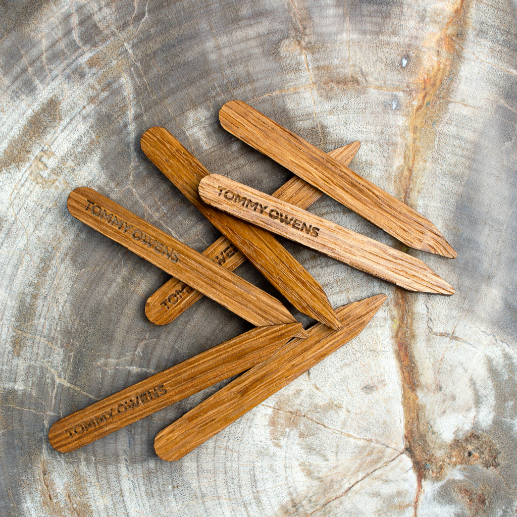 Oak wood collar stays scattered amongst acorns and oak leaves, emphasizing their natural origins and classic appeal.