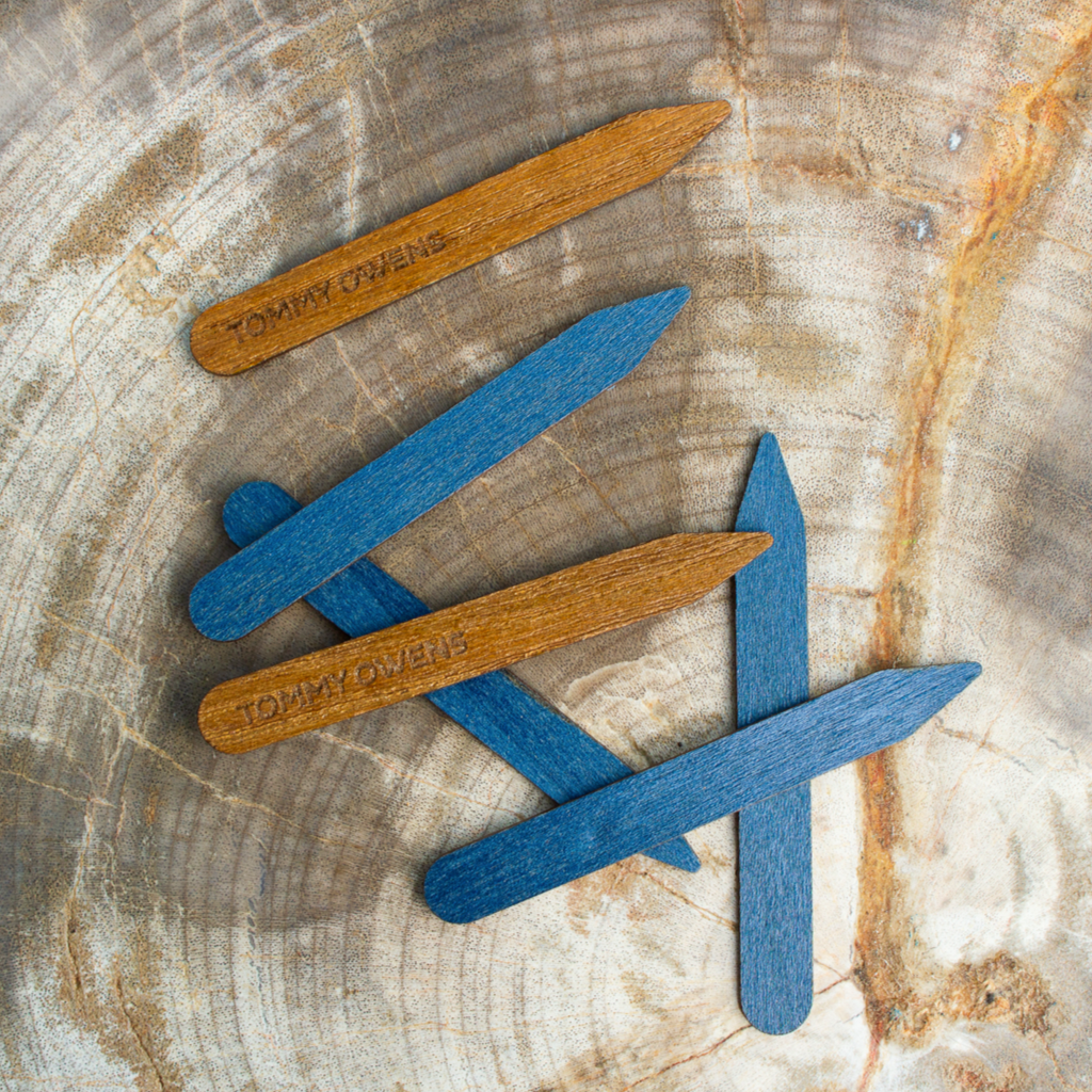 Teak and blue maple collar stays scattered on a beach scene, reflecting the natural elements of wood and water.