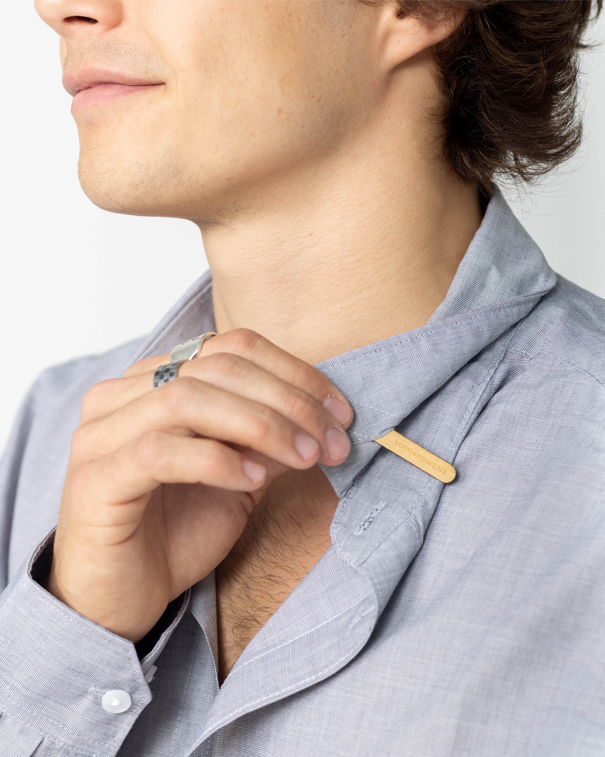 Man inserting a maple collar stay into his dress shirt, demonstrating the proper way to achieve a crisp and polished collar.