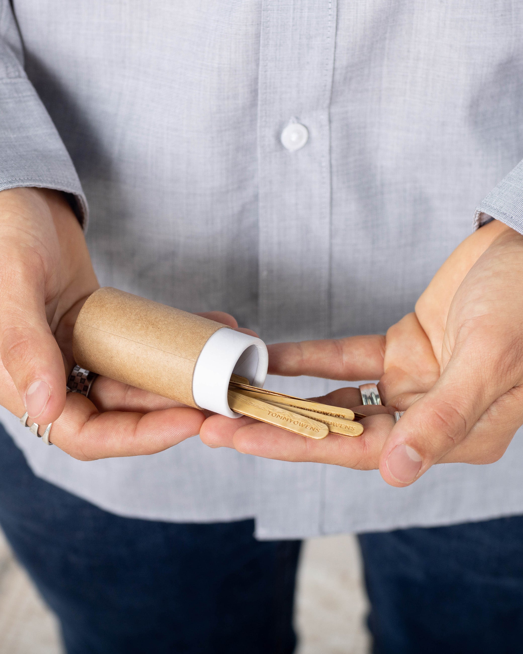 A man holding a package of handcrafted maple collar stays, with a few stays peeking out, highlighting the natural beauty of the wood.